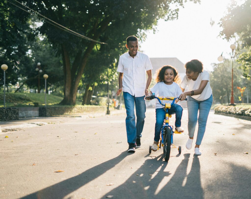Homem ao lado da sua mulher a ensinar o seu filho a andar de bicicleta